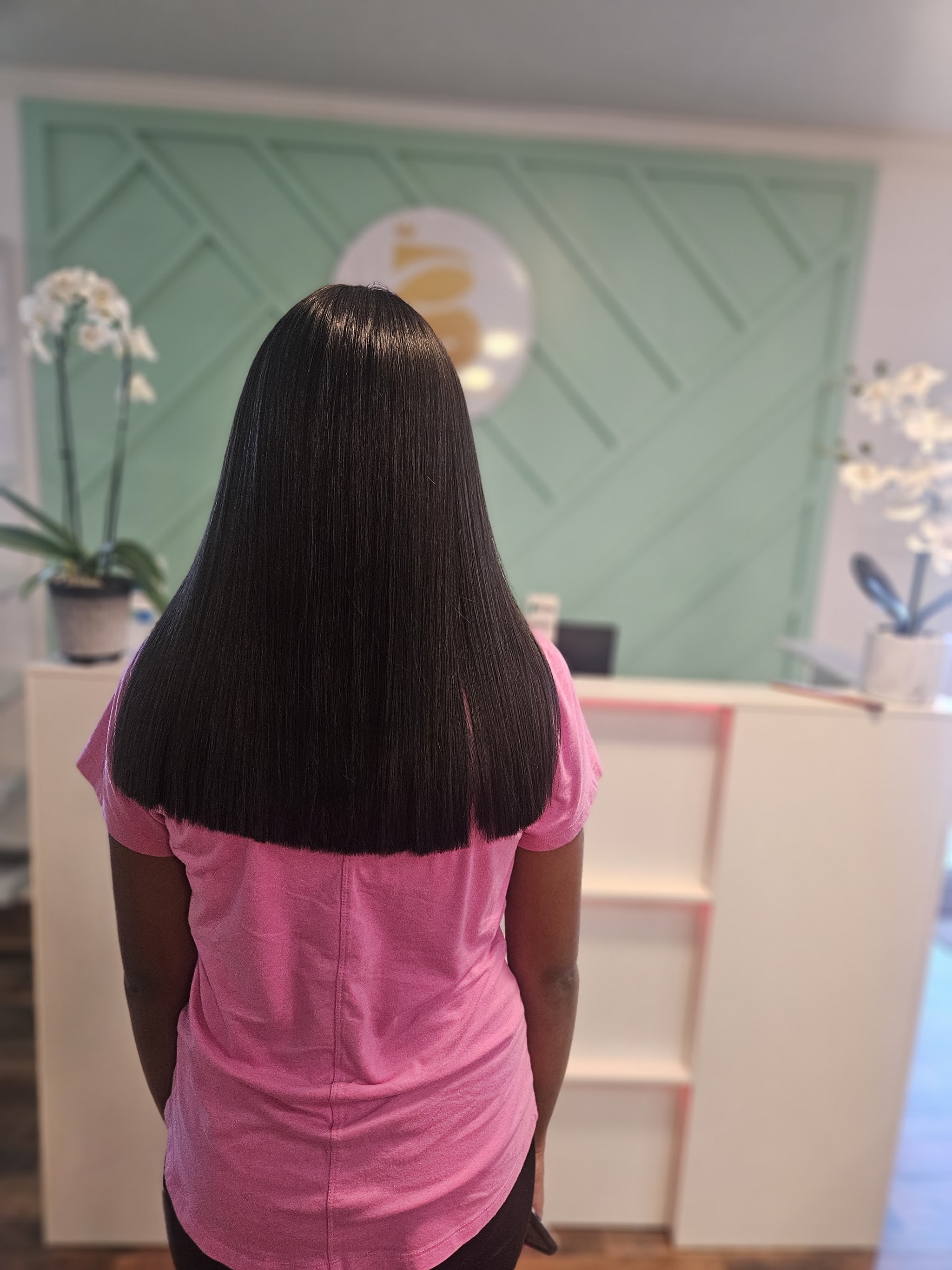 Sleek straight dark hair in front of the mint reception wall